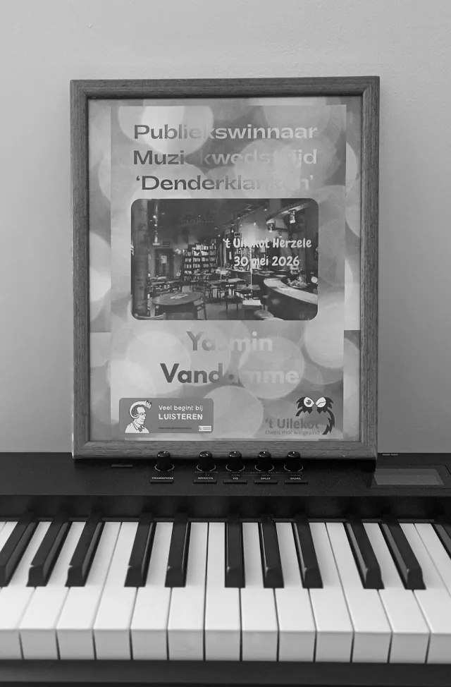 Audience award certificate for music contest Denderklanken, awarded to Yasmin Vandamme, resting on a piano keyboard, black-and-white