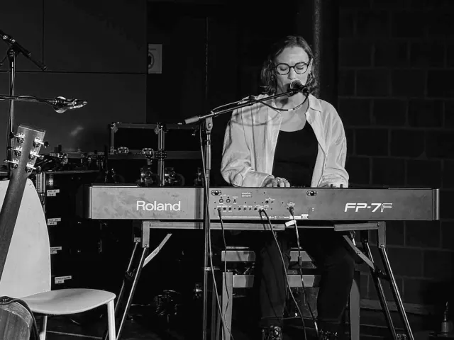 Yasmin playing a Roland keyboard and singing at music contest Goeie Vangst, black-and-white